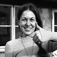Svartvit bild på Katarina som ler och gör tummen upp mot kameran.