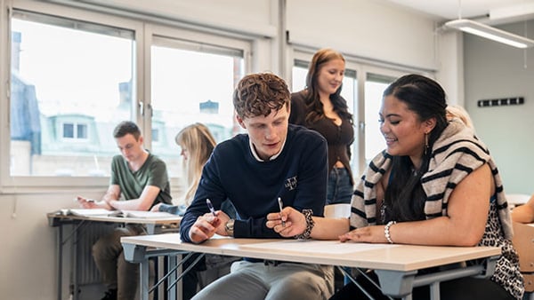 Två elever som sitter i ett klassrum och studerar tillsammans.