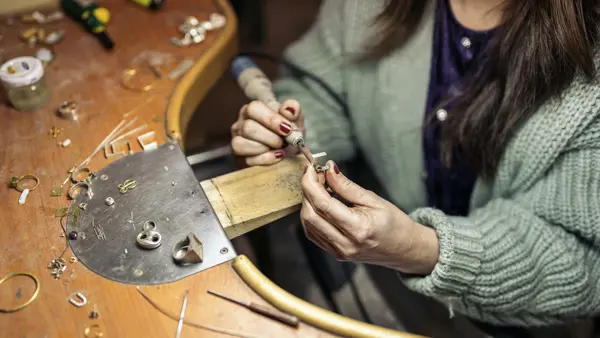 En kvinna arbetar med ett silversmycke.