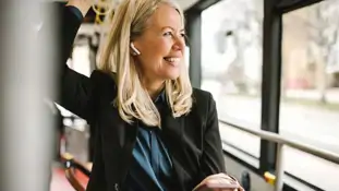 Kvinna som står på en buss och ler