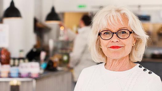Glad kvinna i förgrunden till en kurs på Pensionärsuniversitetet i Gävle