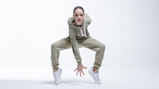 Dansare i grå kläder mot en vit bakgrund. 