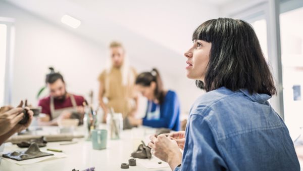 Multi-ethnic group of people learning ceramic art. They are modeling clay for making ceramic works