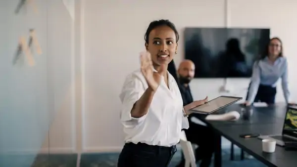 En kvinna som håller ett föredrag inför en grupp människor.