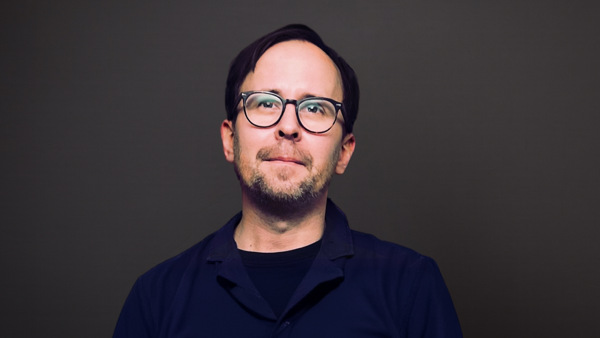 Gunnar bär glasögon och blå skjorta.