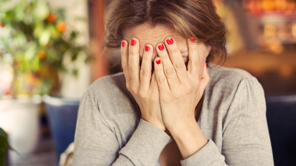 En kvinna håller händerna för ansiktet.