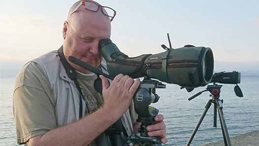 Fågelskådaren Peter Berglin står framför en kikare.