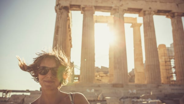 En kvinna står framför ruinerna av en byggnad.