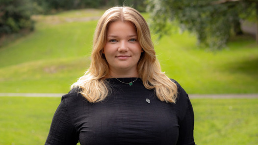 En kvinna i svart topp står på ett fält.