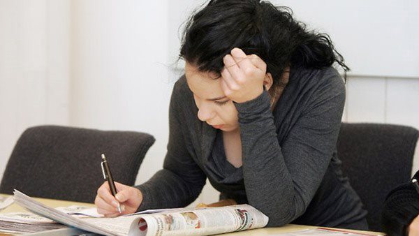 En kvinna sitter böjd över en anteckningsbok.