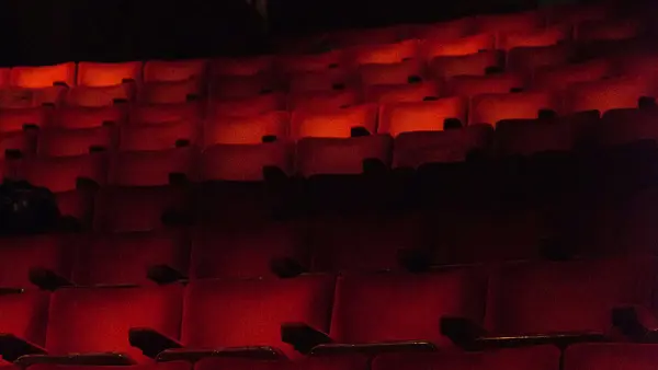 En biosalong full med röda tomma biostolar i svagt ljus