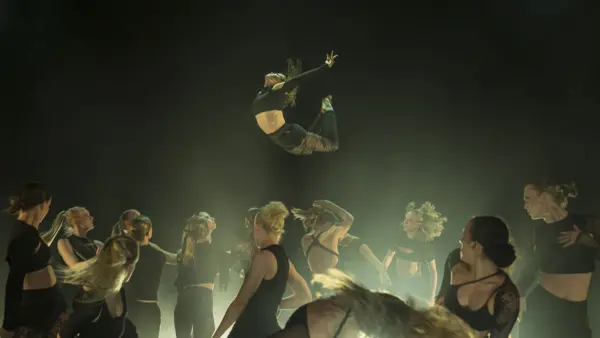 En grupp med dansare i svarta kläder på en scen. 