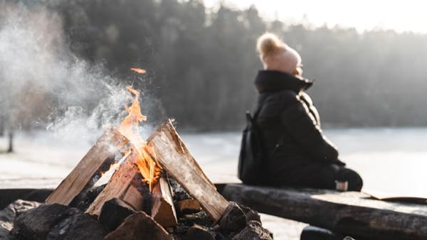 En kvinna sitter framför en lägereld 