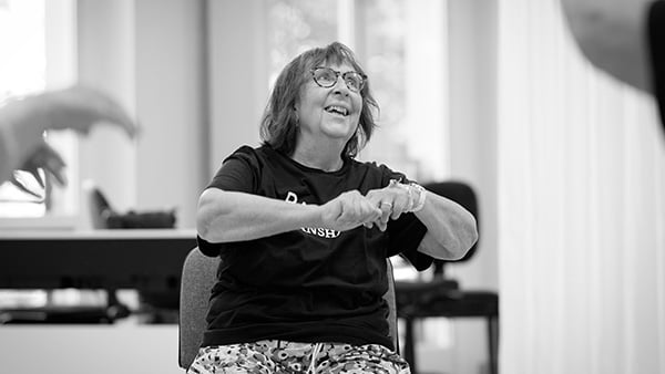 Glad kvinna som sitter på en stol och dansar på Balettakademien Stockholm