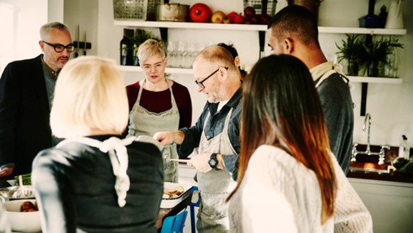 Chef teaching cooking class to group of friends