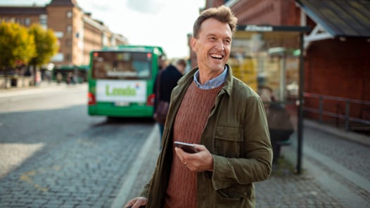 En man står på en gata och håller i en mobiltelefon.