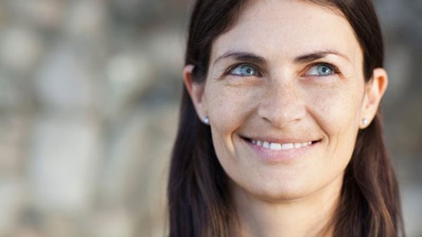 Närbild av kvinna med ett stort leende - deltar i kurs i svenska på Folkuniversitetet