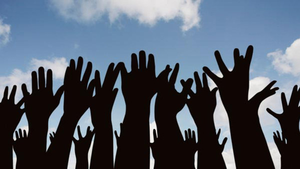 Siluetter av uppsträckta händer mot blå himmel - symbol för föreningslivs, engagemang och demokrati